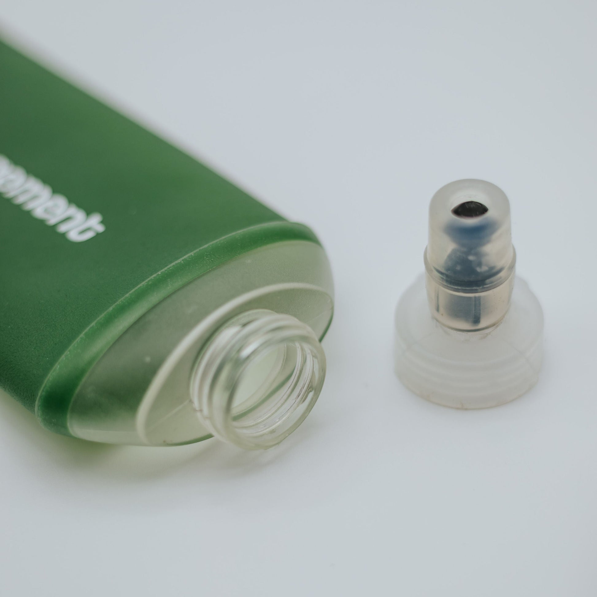 Green and clear soft flasks with a cap on a white background