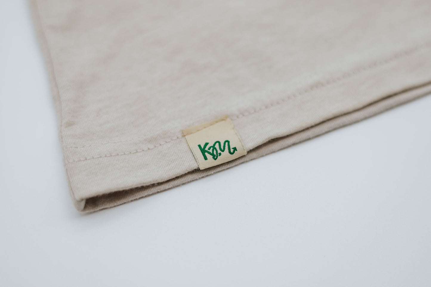 Close-up of a beige fabric with a brand label 
'KM' on a white background