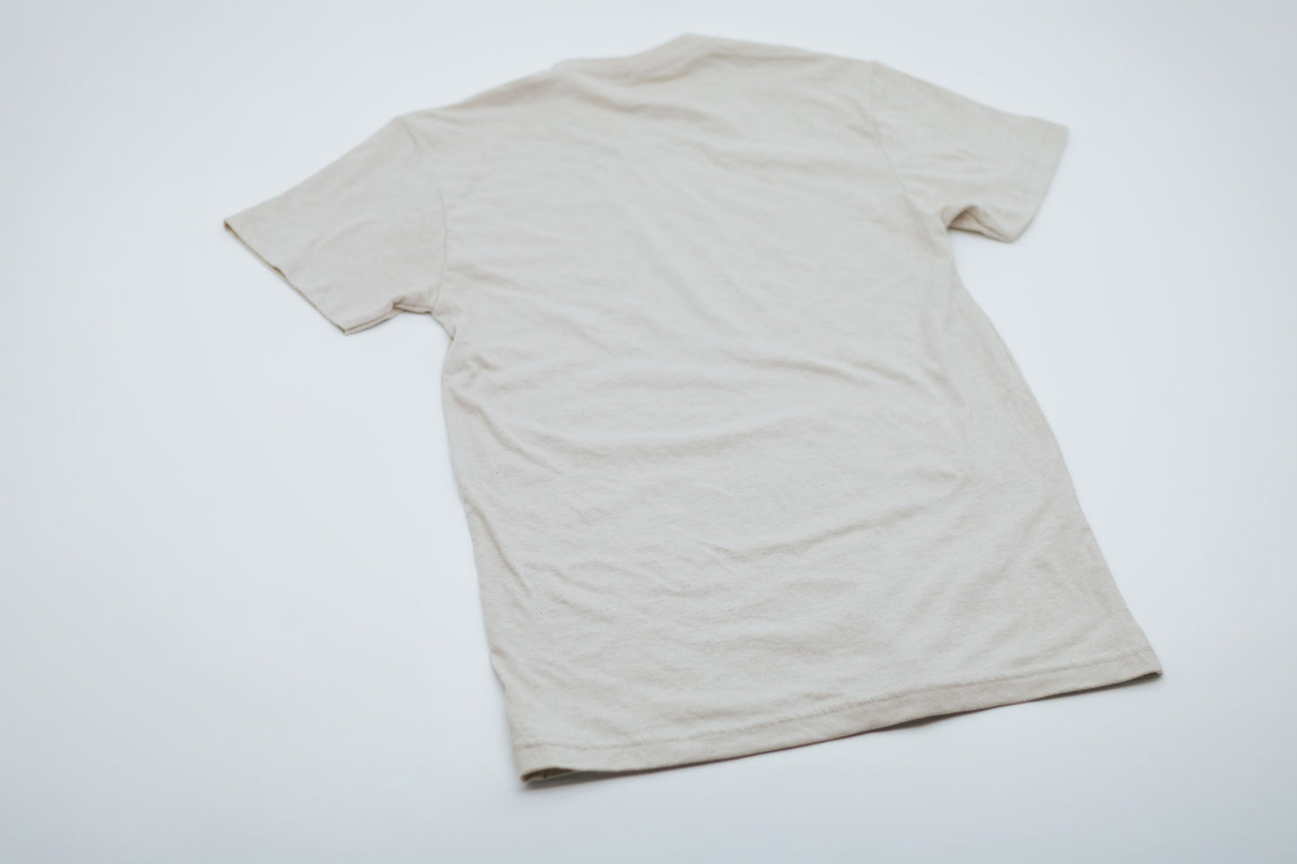 The back of a beige t-shirt on a white background