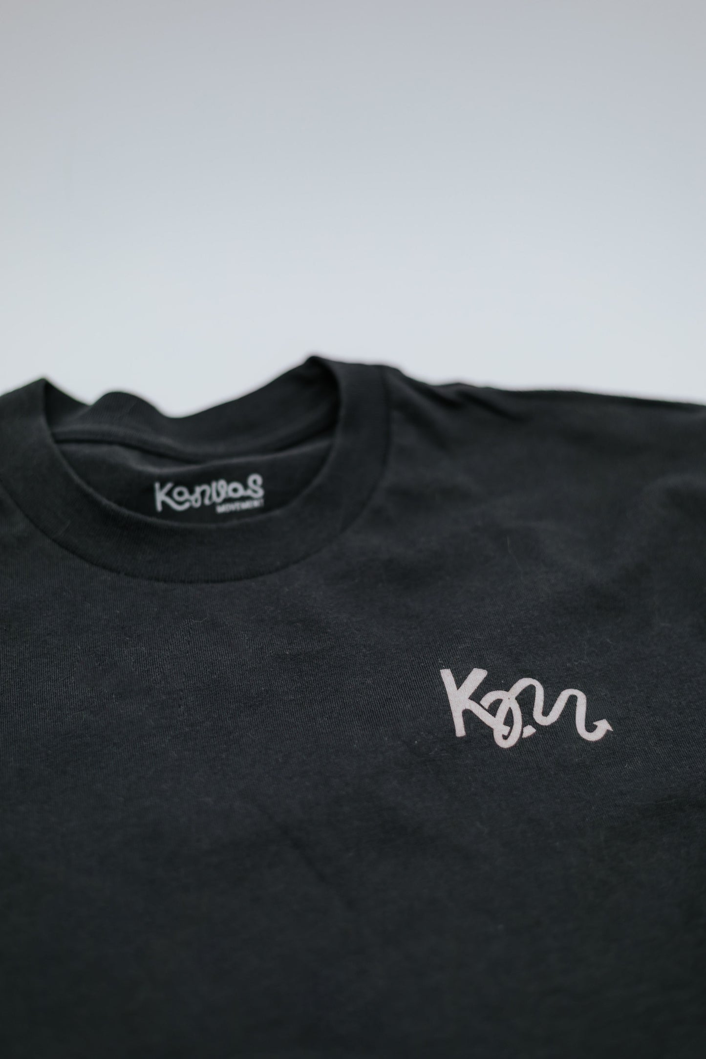 Black t-shirt with white logo on a light gray background
