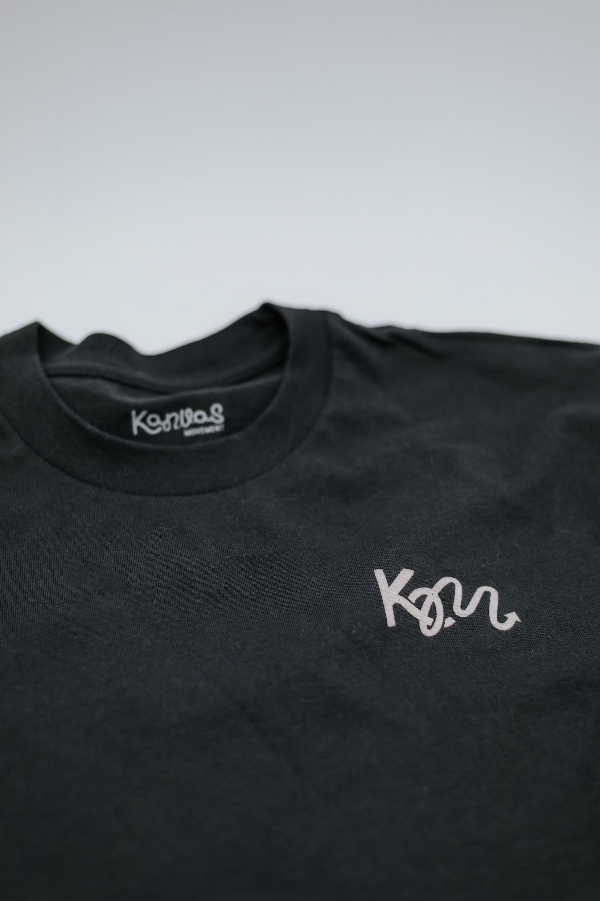 Black t-shirt with white logo on a light gray background