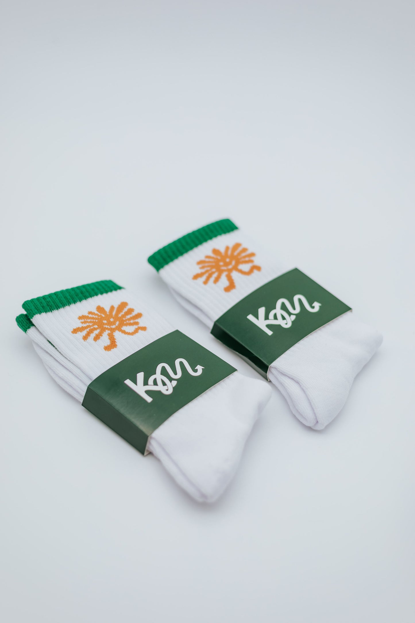 White socks with green and orange accents on a light gray background