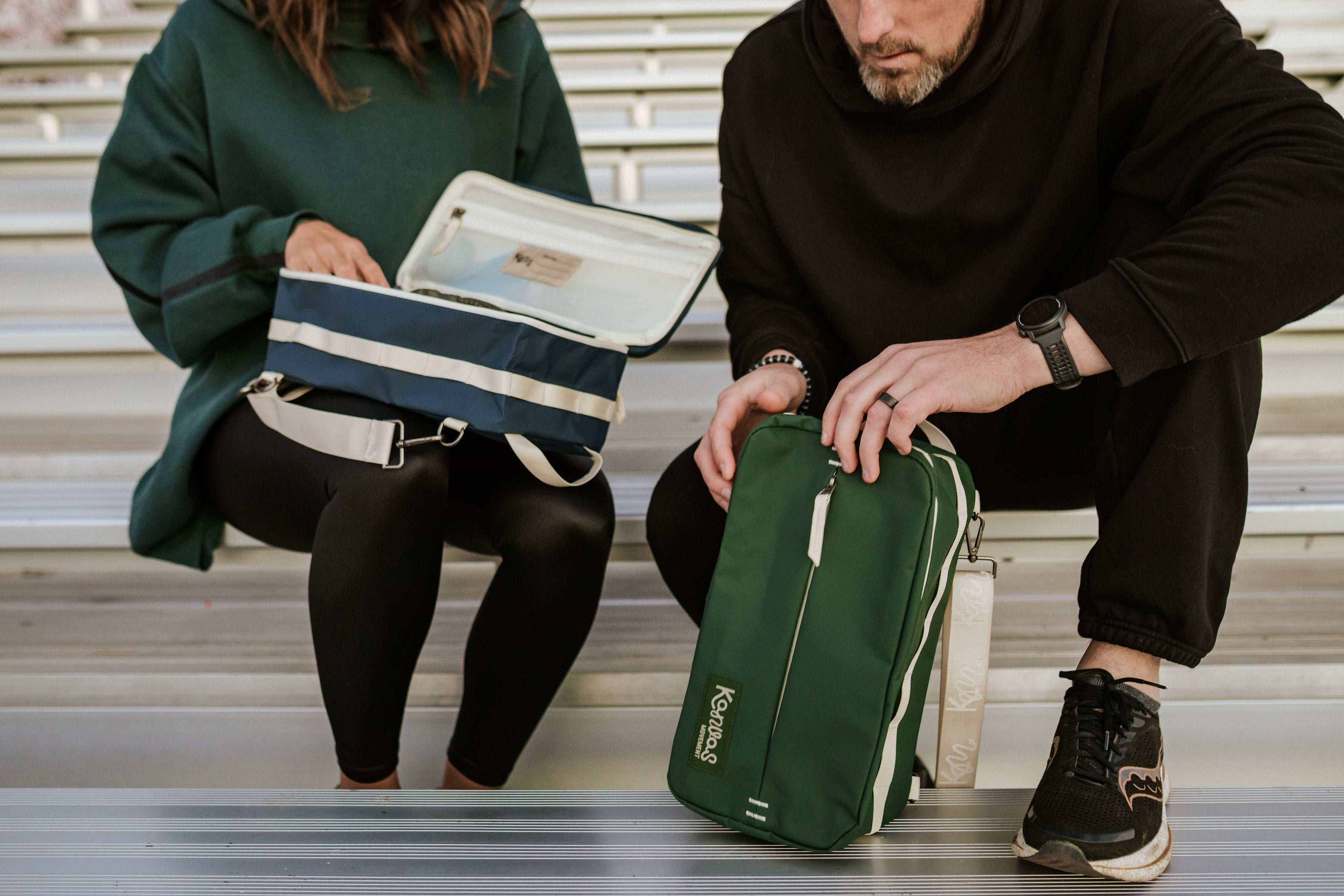 Two people sitting on steps with green and blue bags.