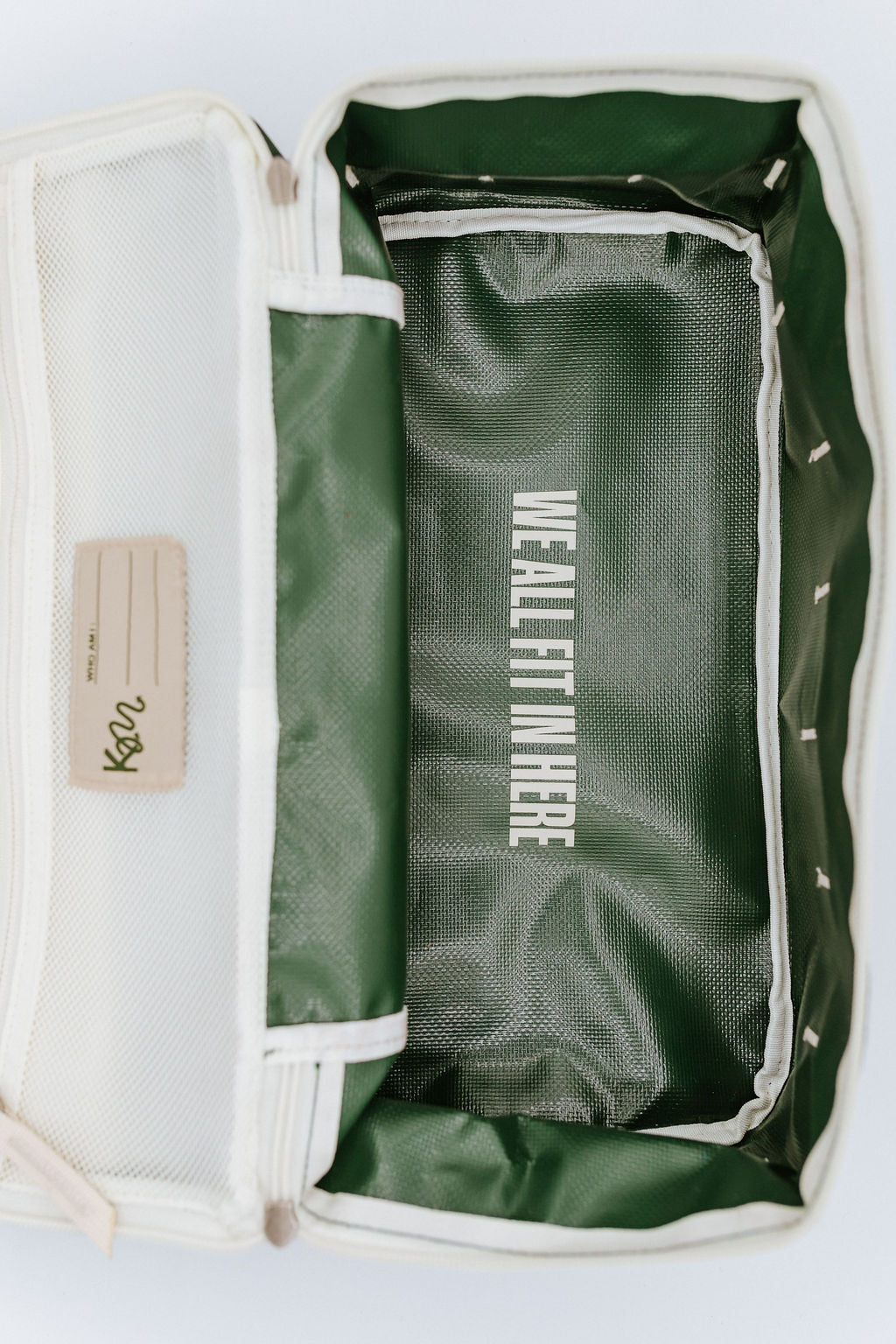 Green bag with white text inside bag that says "we all fit in here", on a light gray background