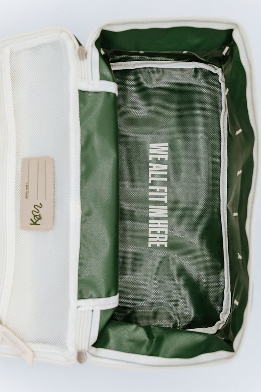 Green bag with white text inside bag that says "we all fit in here", on a light gray background