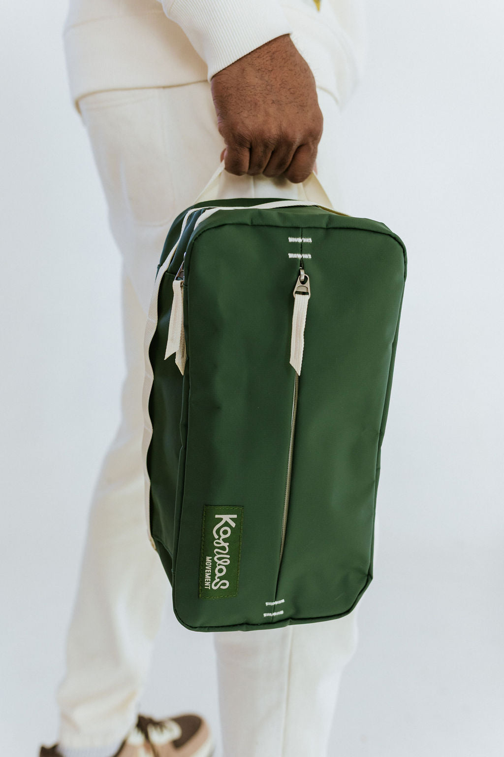 Green shoe bag with 'Kanvas Movement' branding held by a person on a white background