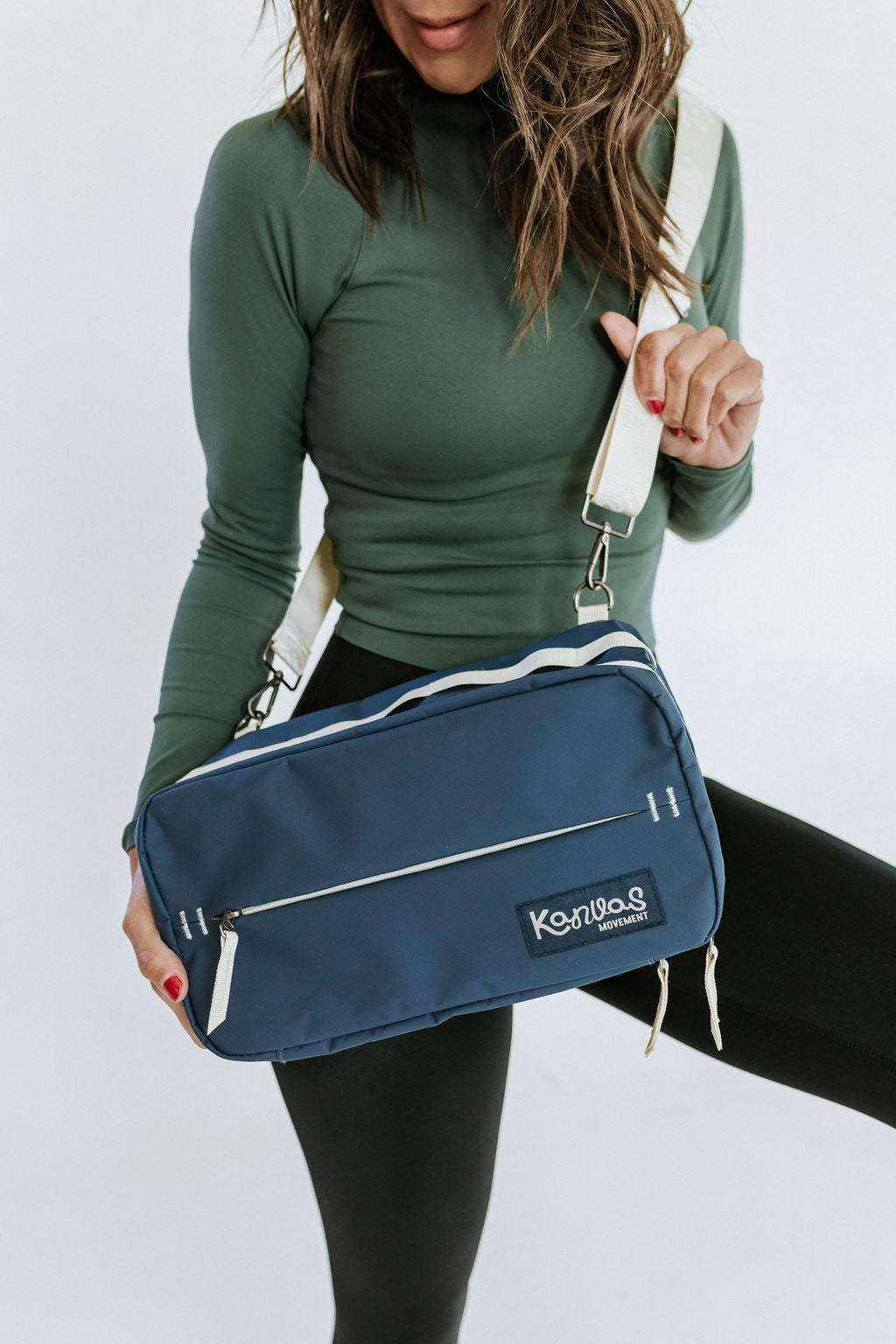 Person holding a blue bag with cream accents, featuring the brand 'Kanvas Movement', against a plain background.